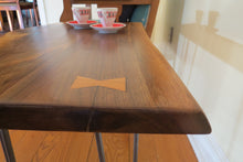 Load image into Gallery viewer,  live edge side or accent table comprised of black walnut slab with hand-forged hairpin legs for a cool mid-century modern look. Slab is hand finished and accented with a single cherry bowtie inlay