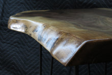 Load image into Gallery viewer,  live edge side or accent table comprised of black walnut slab with hand-forged hairpin legs for a cool mid-century modern look. Slab is hand finished and accented with a single cherry bowtie inlay