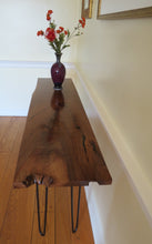 Load image into Gallery viewer, live edge console or hall table, comprising of beautifulhand finished black walnut board atop tall hand-forged hairpin legs for a cool mid-century modern look