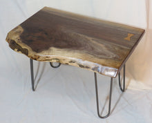 Load image into Gallery viewer,  live edge side or accent table comprised of black walnut slab with hand-forged hairpin legs for a cool mid-century modern look. Slab is hand finished and accented with a single cherry bowtie inlay