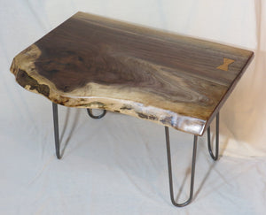  live edge side or accent table comprised of black walnut slab with hand-forged hairpin legs for a cool mid-century modern look. Slab is hand finished and accented with a single cherry bowtie inlay